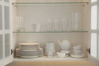 Photo of Cabinet with crockery and glassware. Order in kitchen