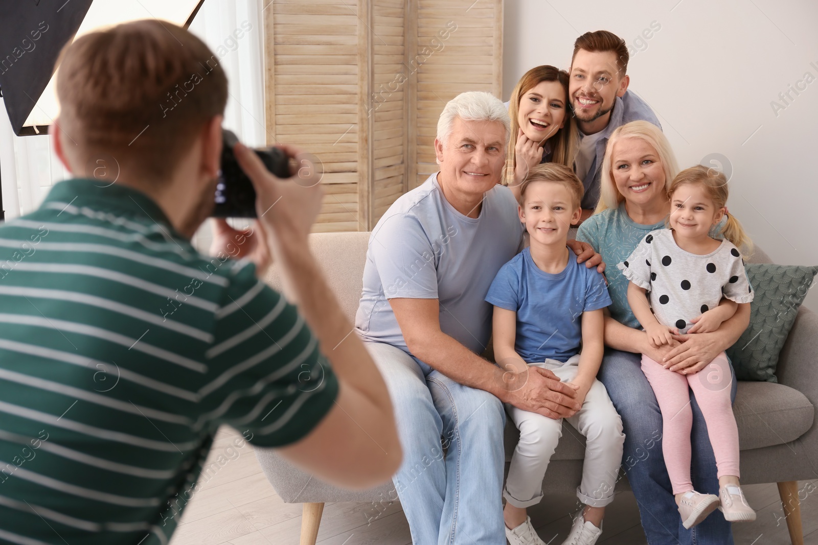 Photo of Professional photographer taking photo of family on sofa in studio