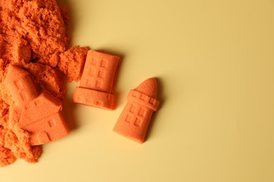 Photo of Castle figures made of orange kinetic sand on beige background, flat lay. Space for text