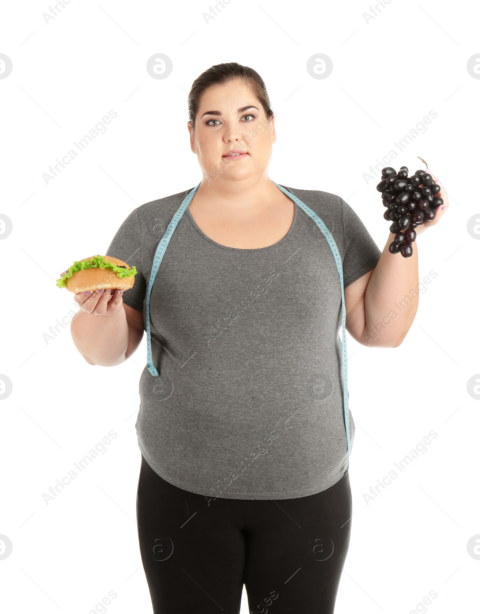 Photo of Overweight woman with hamburger, grapes and measuring tape on white background