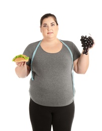 Photo of Overweight woman with hamburger, grapes and measuring tape on white background