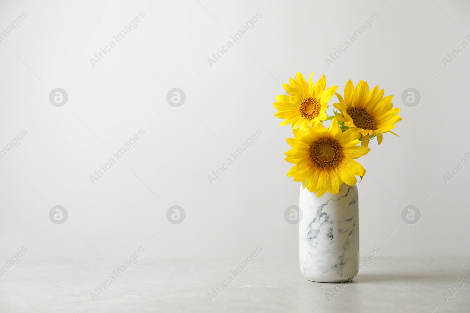 Photo of Vase with beautiful yellow sunflowers on table