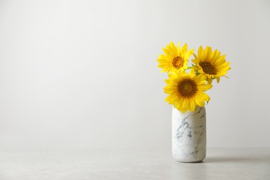 Photo of Vase with beautiful yellow sunflowers on table