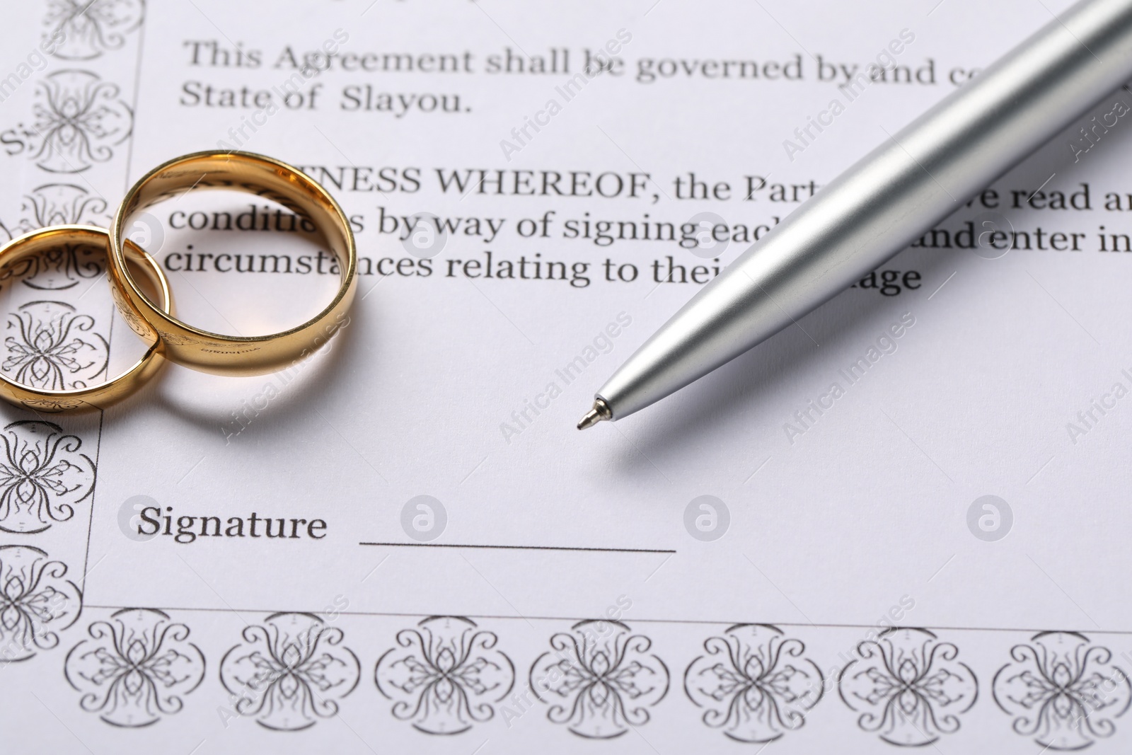Photo of Marriage contract, gold rings and pen on table, closeup