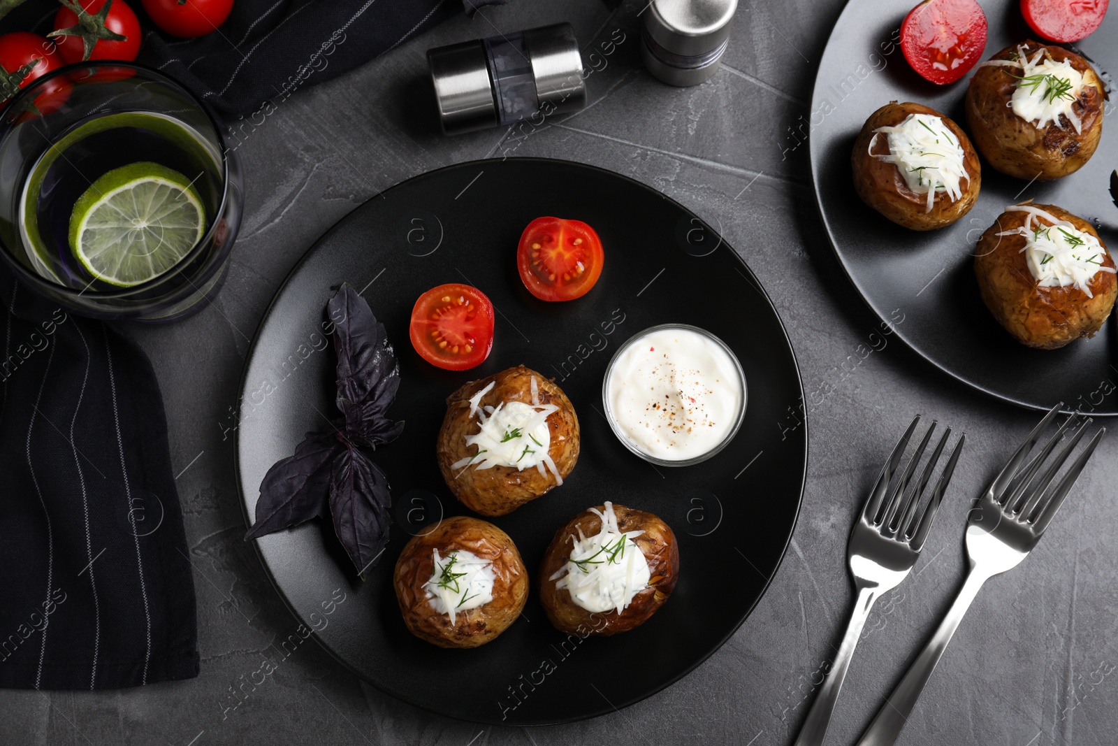 Photo of Delicious hot baked potato with sour cream dressing on grey table, flat lay