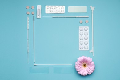 Photo of Frame of many gynecological pills, tools and gerbera flower on light blue background, flat lay. Space for text