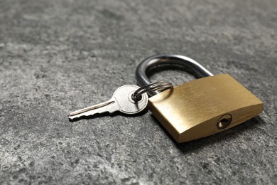 Photo of Steel padlock with key on grey table, closeup. Space for text