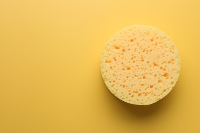 Photo of Sponge on yellow background, top view. Space for text