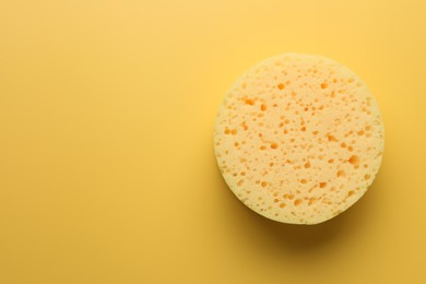 Sponge on yellow background, top view. Space for text