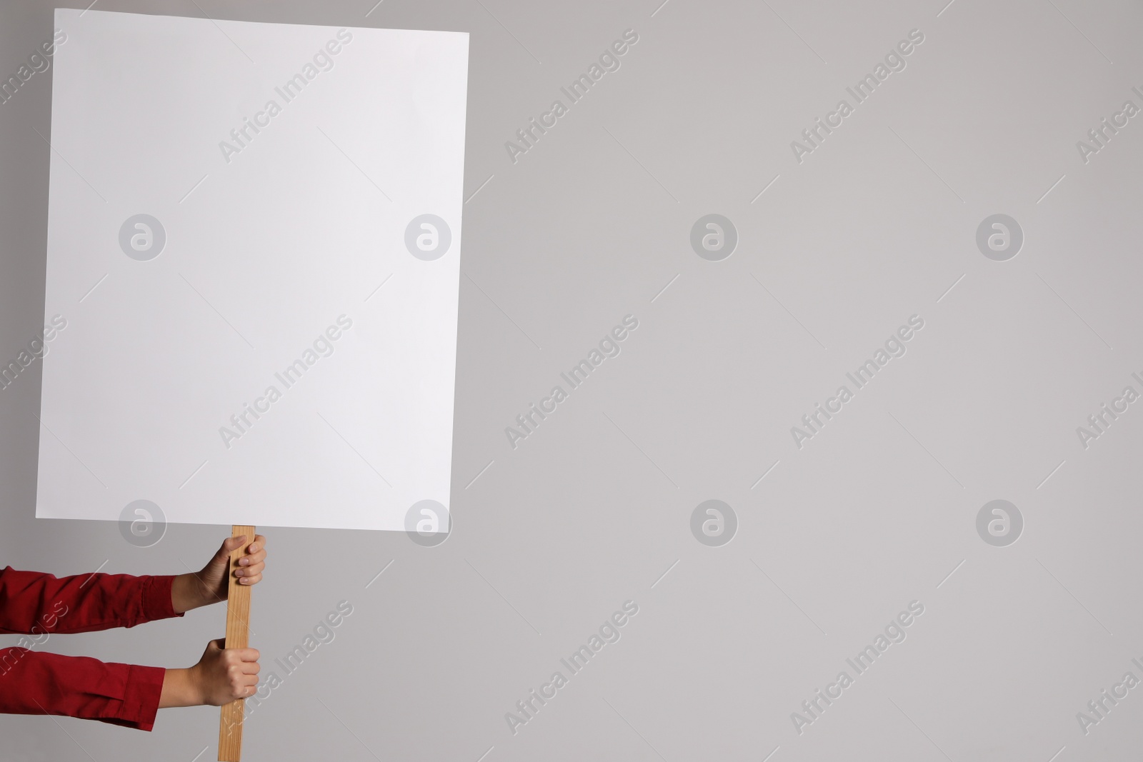 Photo of Woman holding blank sign on light grey background, closeup. Space for design