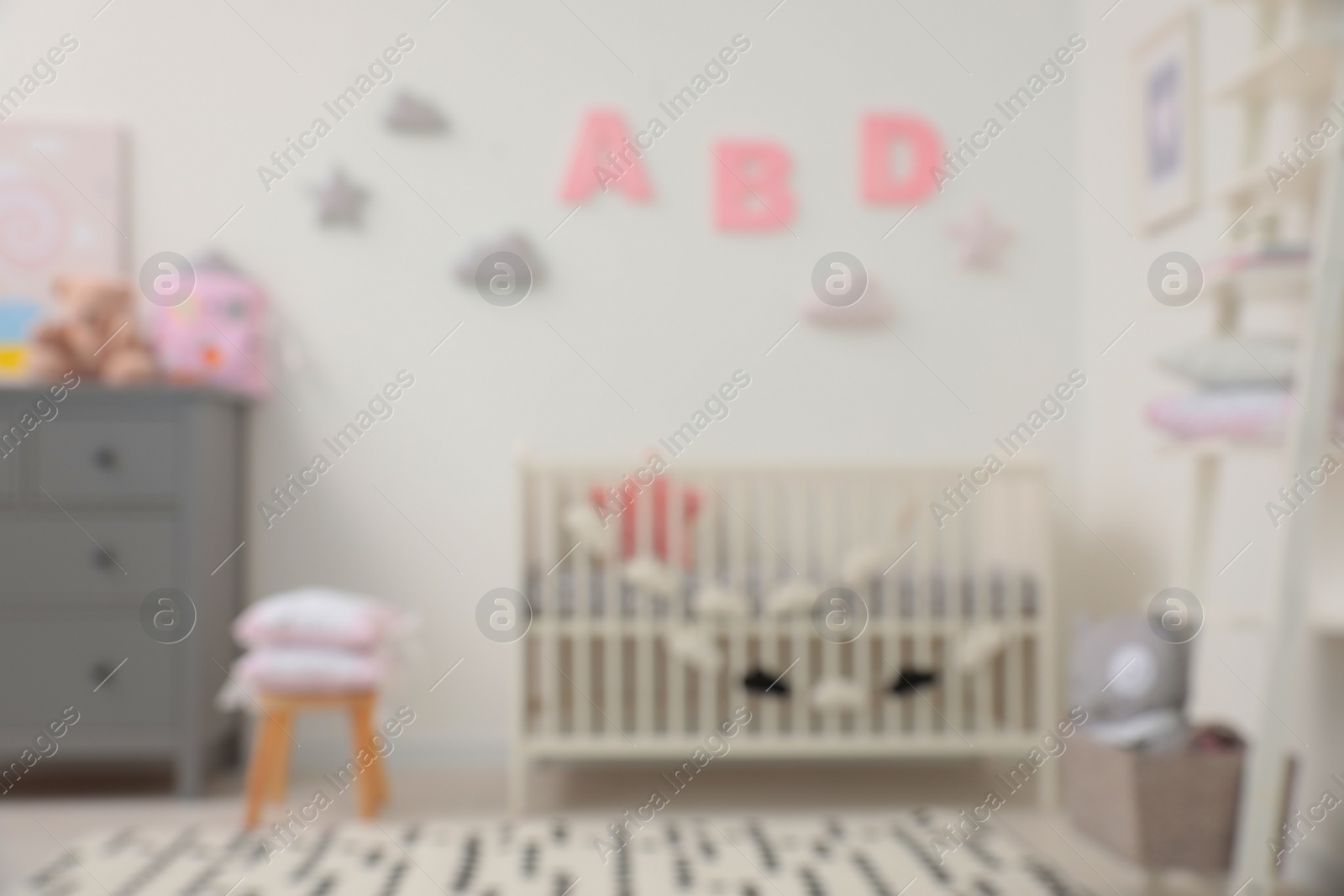 Photo of Blurred view of cute baby room interior with modern crib near white wall