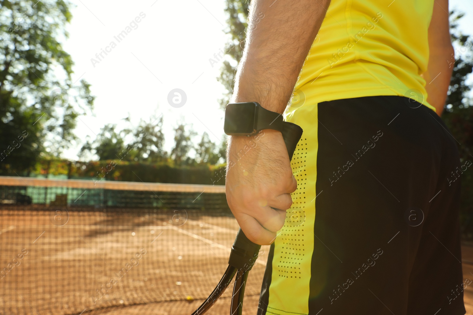 Photo of Man wearing modern smart watch during training on tennis court, closeup