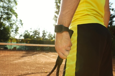 Man wearing modern smart watch during training on tennis court, closeup