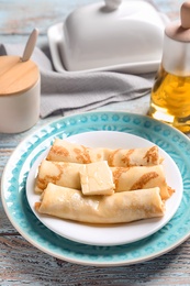 Photo of Thin pancakes with butter on plate, closeup