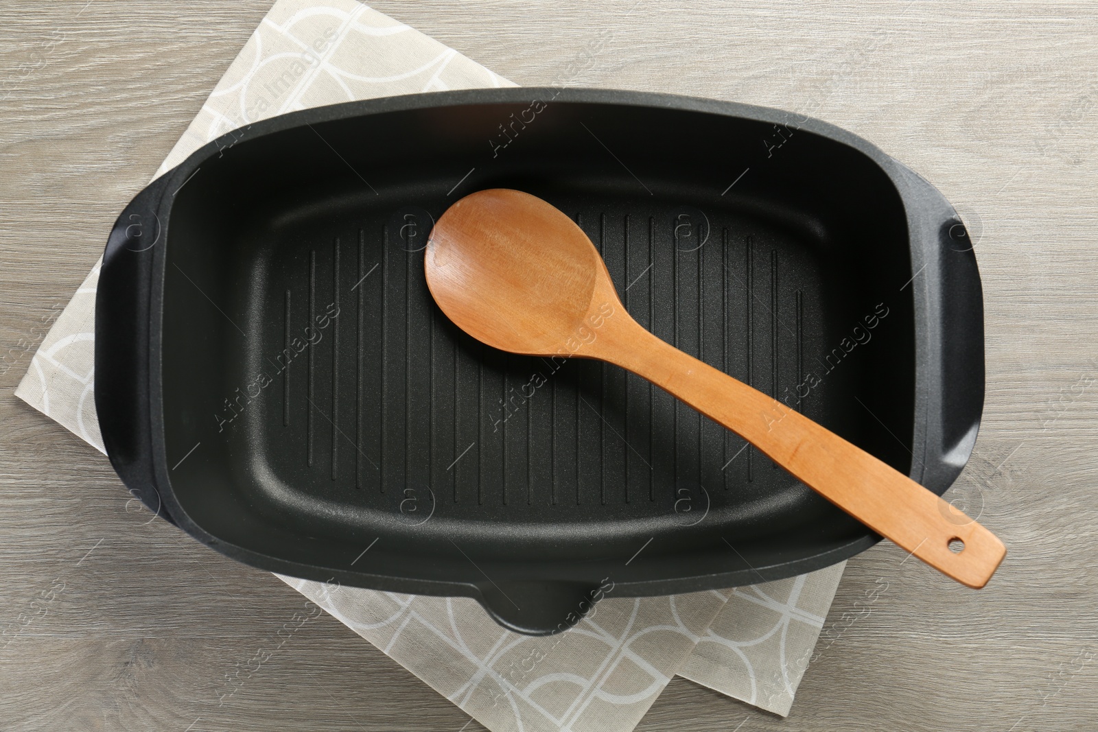 Photo of Black pot and spoon on wooden table, top view