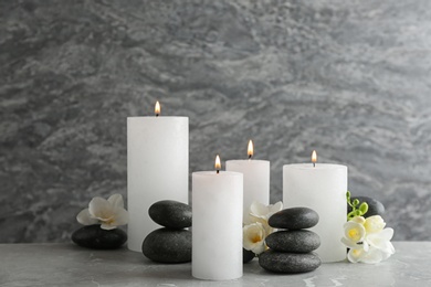 Composition of burning candles, spa stones and flowers on table. Space for text