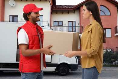 Image of Happy courier giving parcel to receiver outdoors
