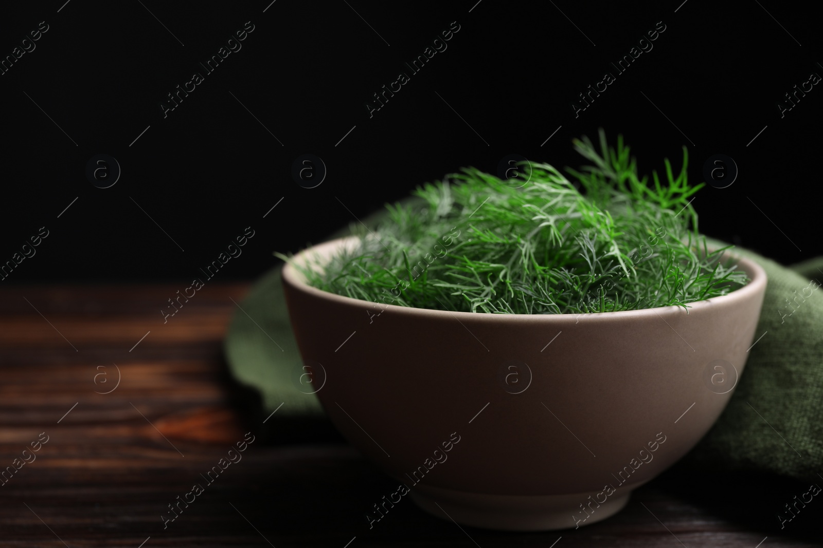 Photo of Bowl of fresh dill on wooden table, closeup. Space for text