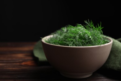 Bowl of fresh dill on wooden table, closeup. Space for text