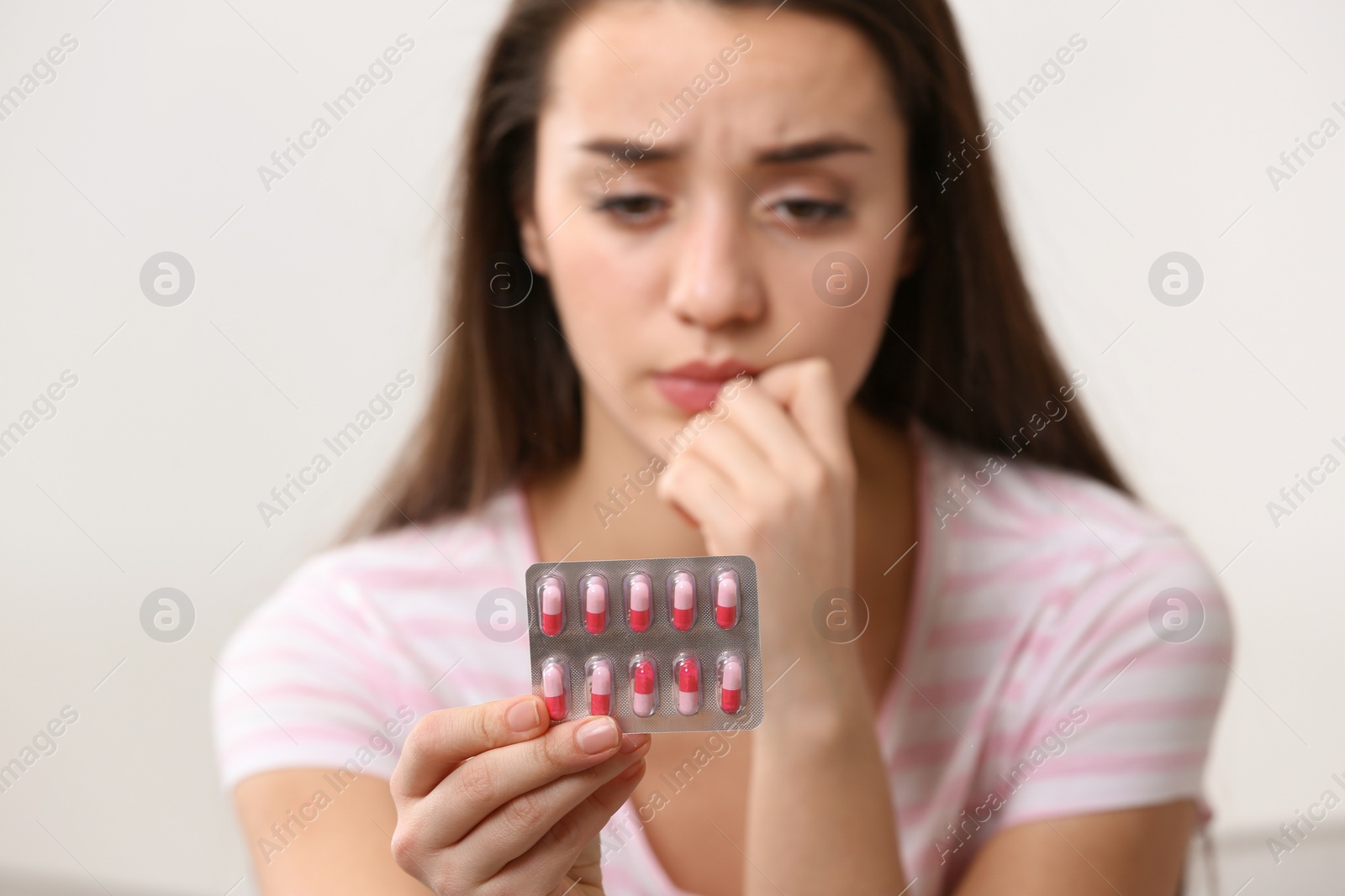 Photo of Young woman with pills on light background, closeup