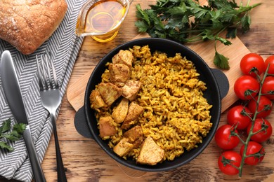 Delicious rice with chicken served on wooden table, flat lay