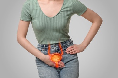 Woman suffering from cystitis on light grey background, closeup. Illustration of urinary system