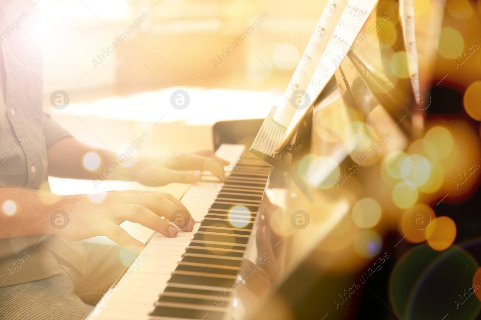 Image of Christmas and New Year music. Man playing piano indoors, closeup. Bokeh effect