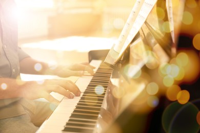 Christmas and New Year music. Man playing piano indoors, closeup. Bokeh effect