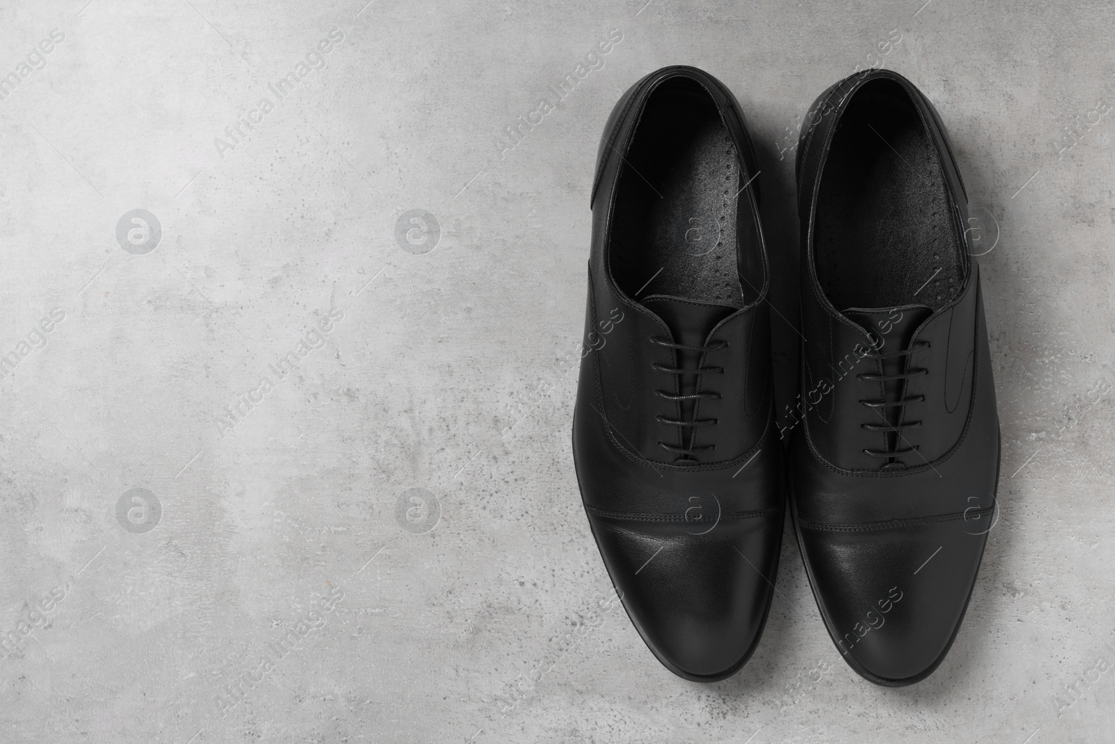 Photo of Pair of black leather men shoes on light grey surface, top view. Space for text