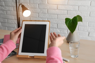 Woman video chatting on tablet at table, closeup. Space for design