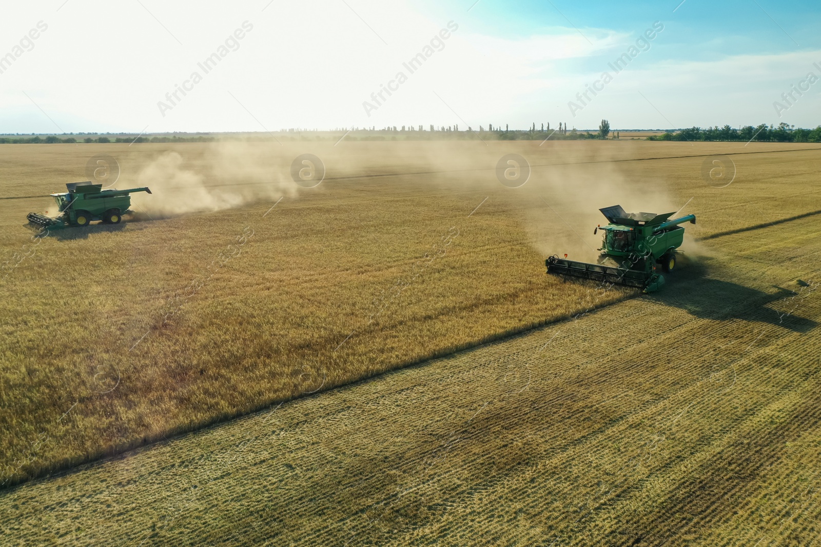 Photo of Modern combine harvesters working in field on sunny day. Agriculture industry