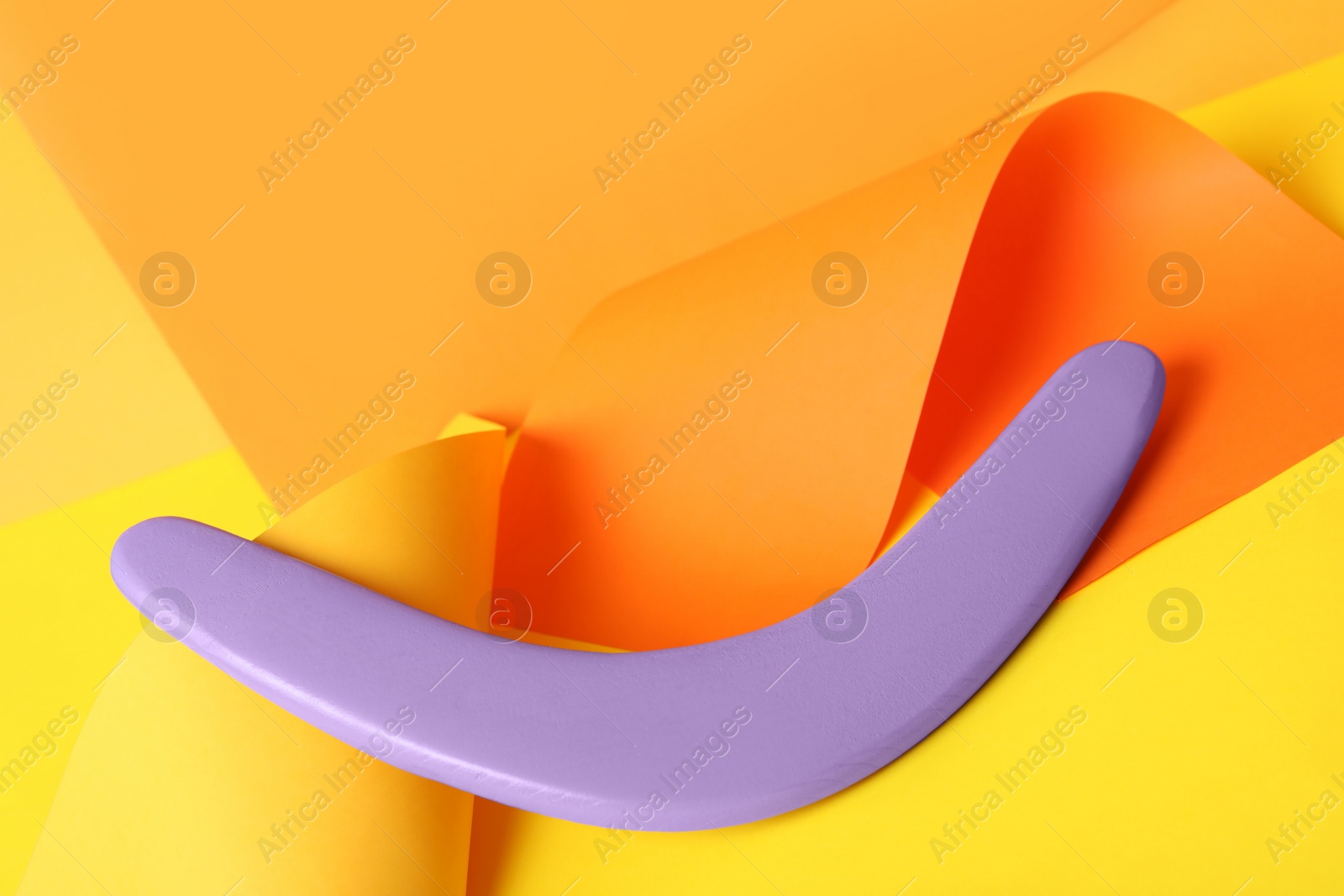 Photo of Creative composition with lilac wooden boomerang on color background