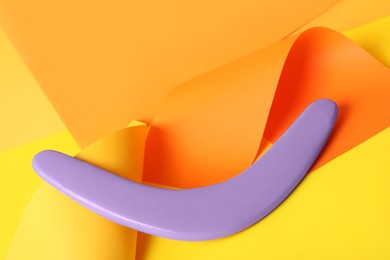 Photo of Creative composition with lilac wooden boomerang on color background