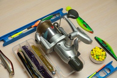 Photo of Different fishing equipment on light wooden table, closeup