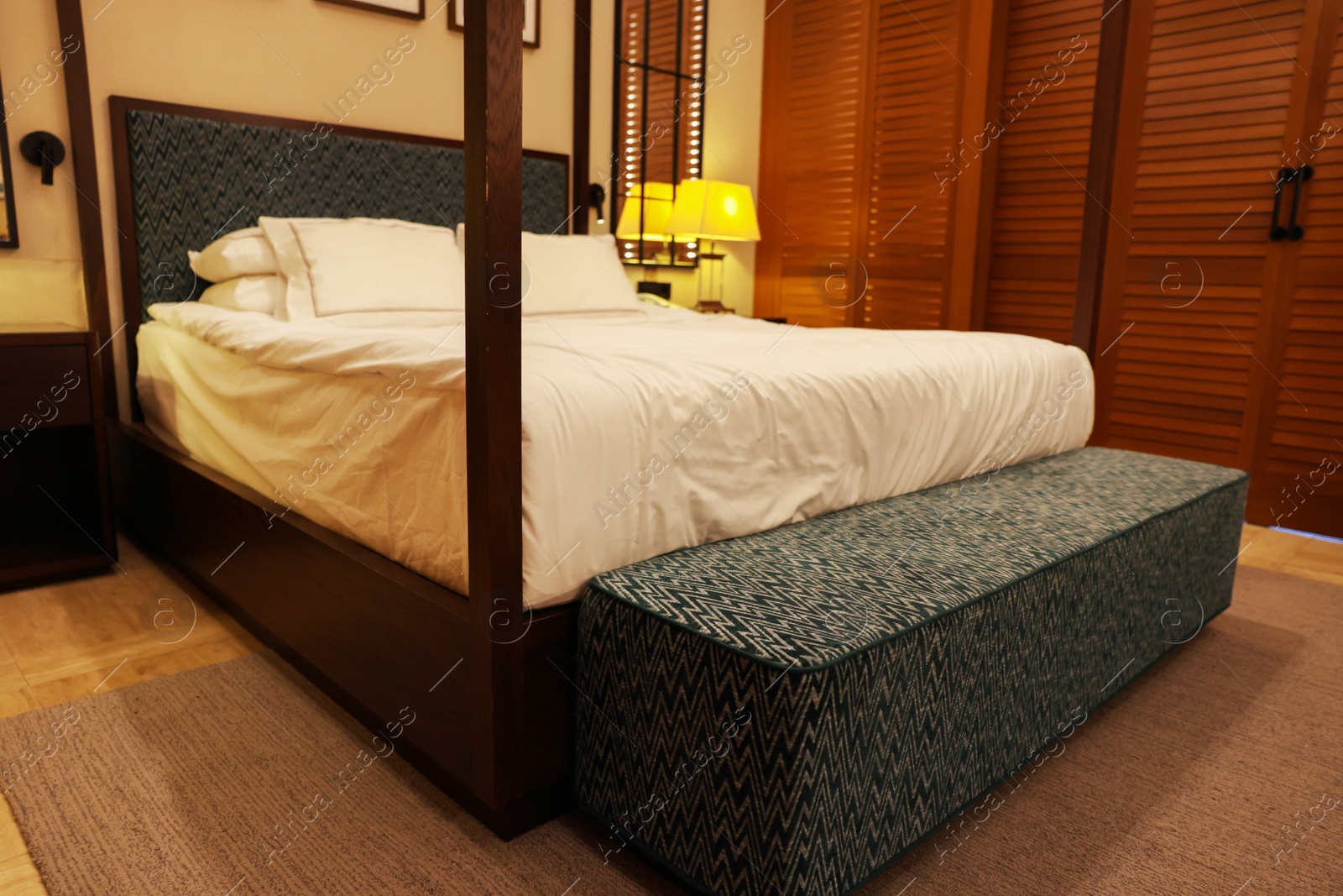 Photo of Large bed with soft bench in comfortable hotel room