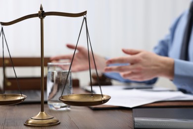 Lawyer working at wooden table, focus on scales of justice