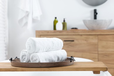 Photo of Rolled bath towels on tub tray in bathroom. Space for text