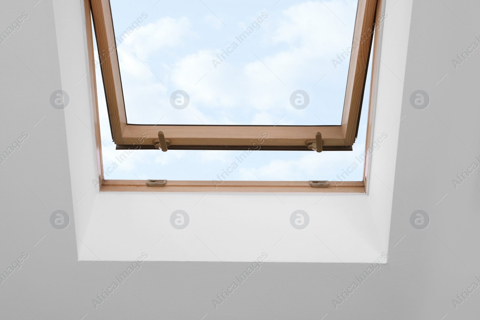 Photo of Skylight roof window on slanted ceiling in attic room, low angle view