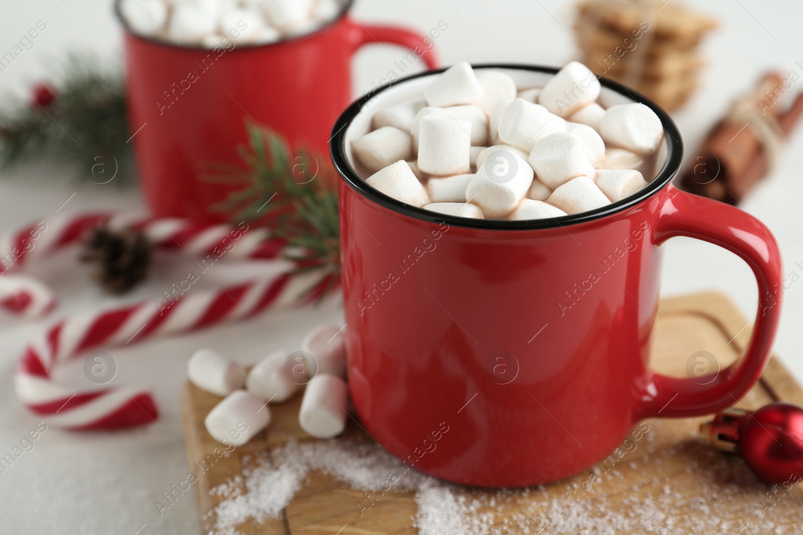 Photo of Hot drink with marshmallows in red cup on white table