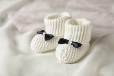 Handmade baby booties with bows on light plaid