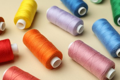 Different colorful sewing threads on beige background