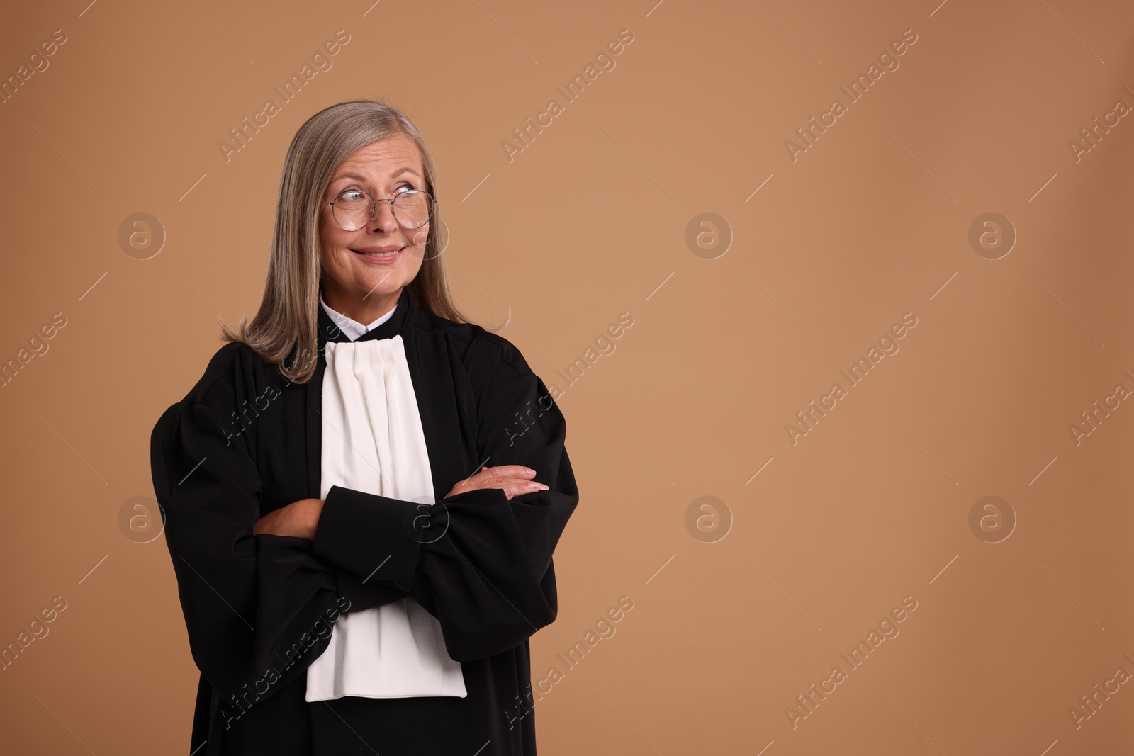 Photo of Smiling senior judge with crossed arms on light brown background. Space for text