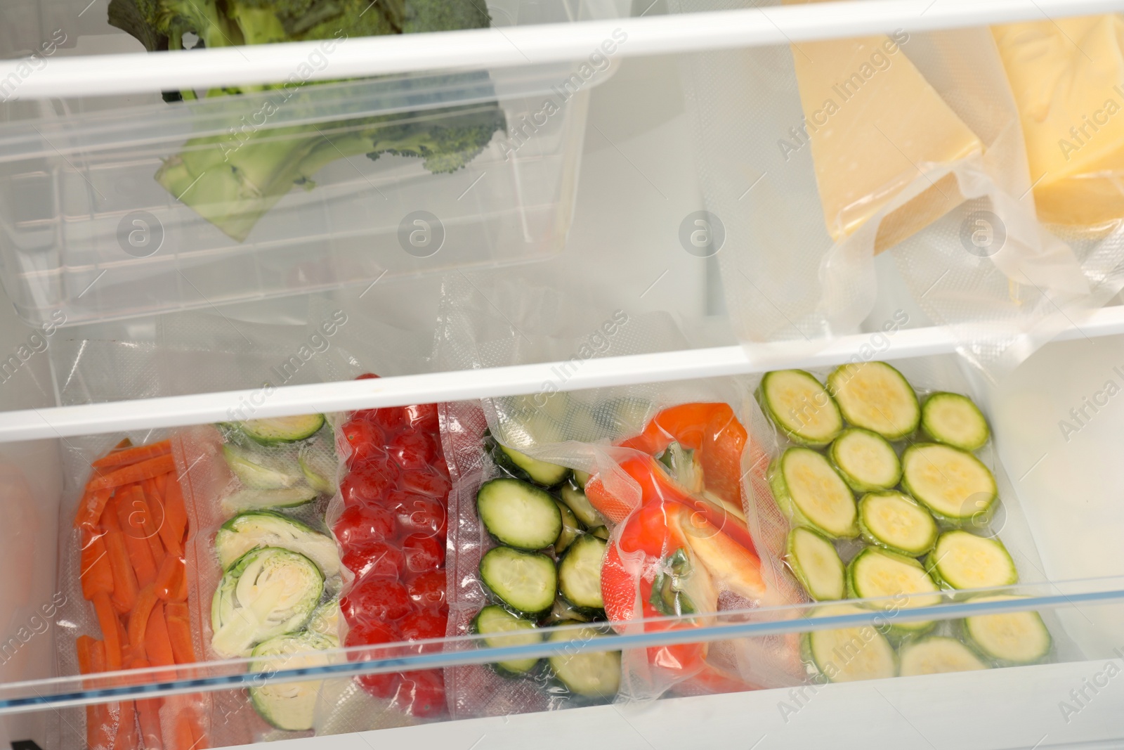 Photo of Vacuum bags with different vegetables in fridge. Food storage