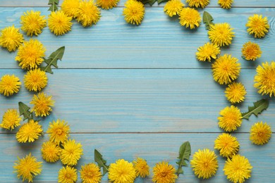 Frame of beautiful yellow dandelions on light blue wooden table, flat lay. Space for text