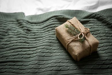 Photo of Decorated gift box on cozy knitted plaid, above view. Space for text