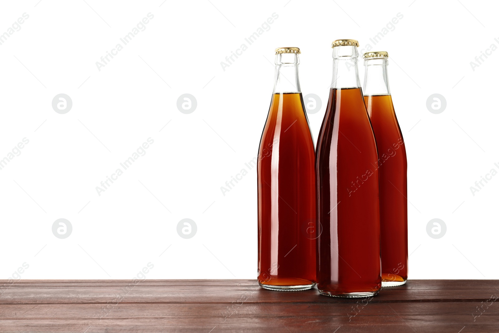 Photo of Bottles of delicious kvass on wooden table against white background