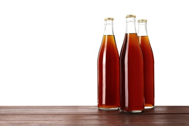 Photo of Bottles of delicious kvass on wooden table against white background