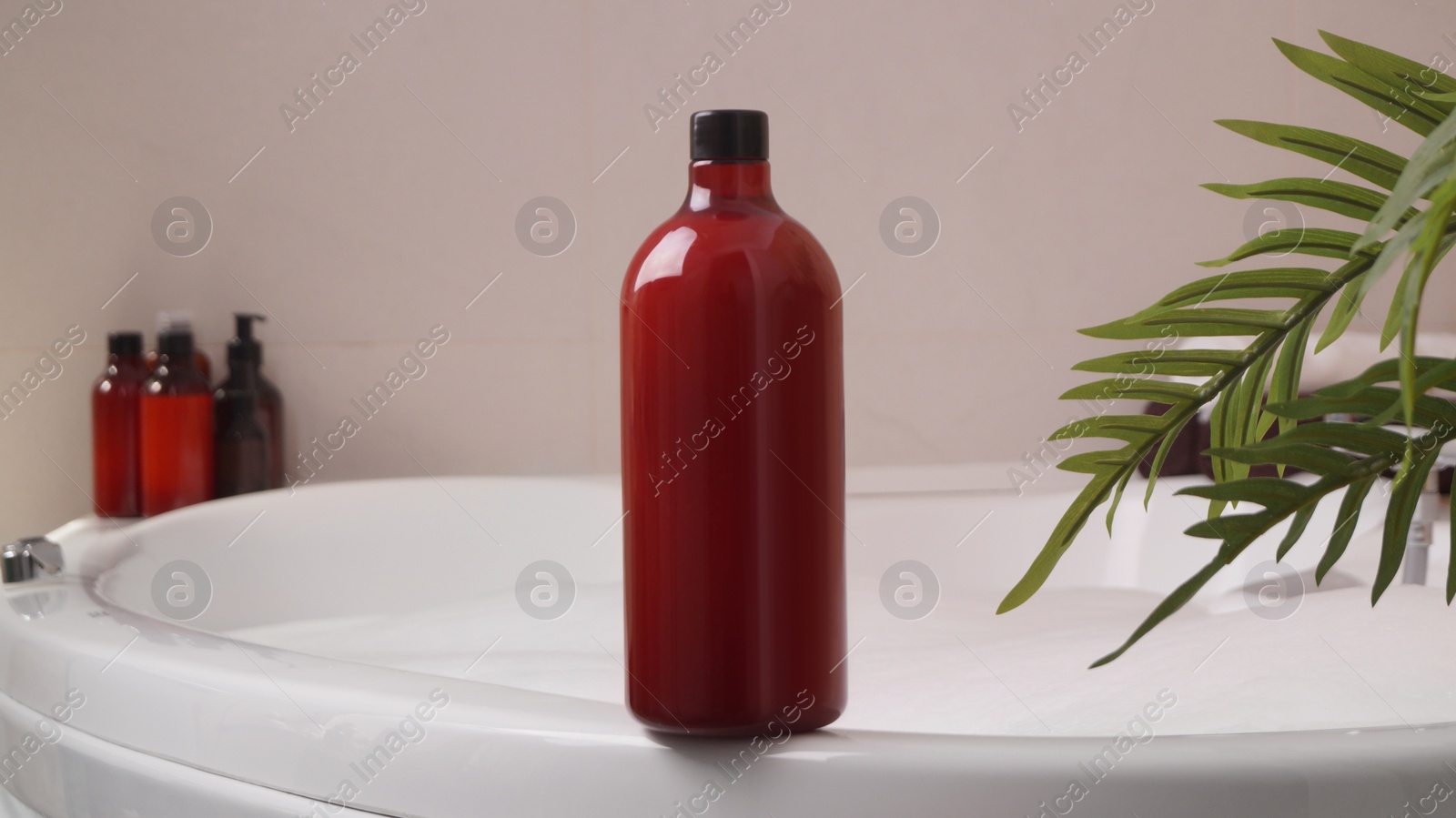 Photo of Red bottle of bubble bath on tub indoors