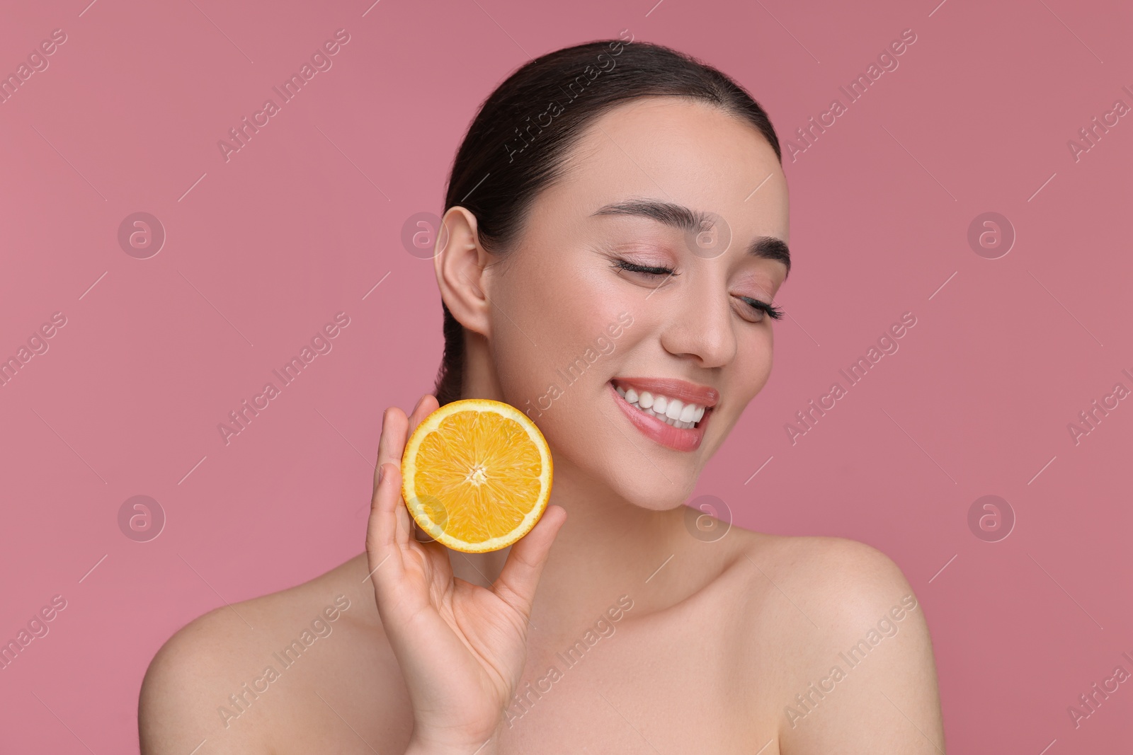 Photo of Beautiful young woman with piece of orange on pink background