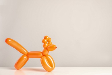 Photo of Animal figure made of modelling balloon on table against color background. Space for text